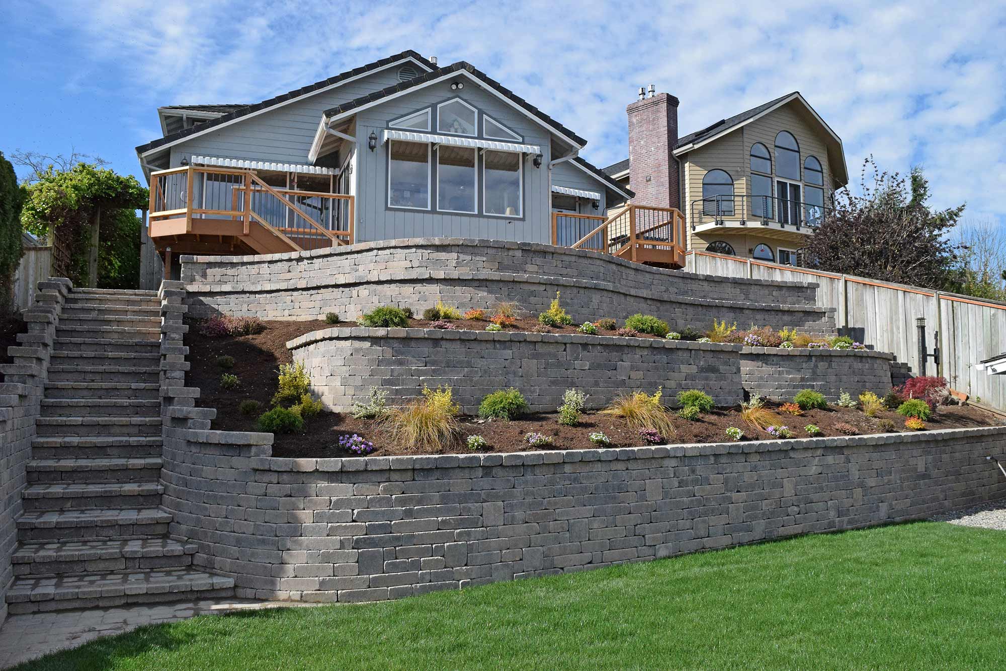 Landscaped garden with a tiered retaining wall, showcasing concrete block wall with structural terraces for erosion control, slopes, and aesthetic appeal in a residential backyard
