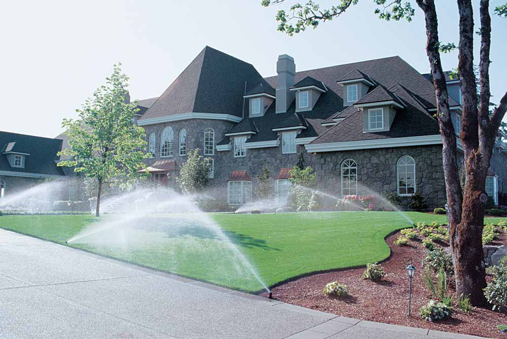 Active Rain Bird or Hunter sprinkler system efficiently watering the lawn of a suburban home, demonstrating water conservation and garden vitality